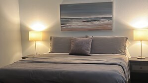 A bedroom with a bed, two bedside lamps, a nightstand, a bench, and a rug. - The Creek House Spacious 4-bedroom house in brilliant Vancouver with WiFi (Vancouver)