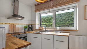 Une cuisine moderne dotée d’une grande fenêtre, d’un plan de travail en bois et de meubles blancs.