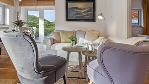 Un salon moderne avec un canapé, des fauteuils, une petite table et un tableau accroché au mur.