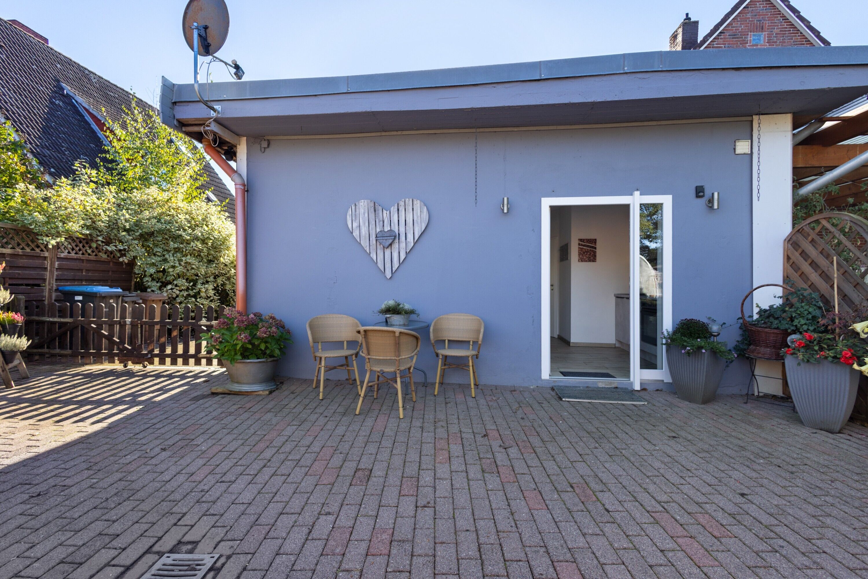 A building with a heart-shaped decoration on the wall, a satellite dish, and a door leading inside.