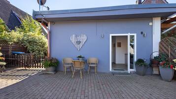 A building with a heart-shaped decoration on the wall, a satellite dish, and a door leading inside.