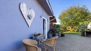 Eine Terrasse mit Korbstühlen, einer herzförmigen Dekoration und Topfpflanzen.