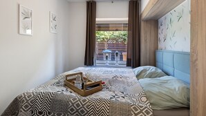 Ein Schlafzimmer mit einem gemusterten Bettbezug, einem Holzkopfteil und Blick auf eine Terrass.