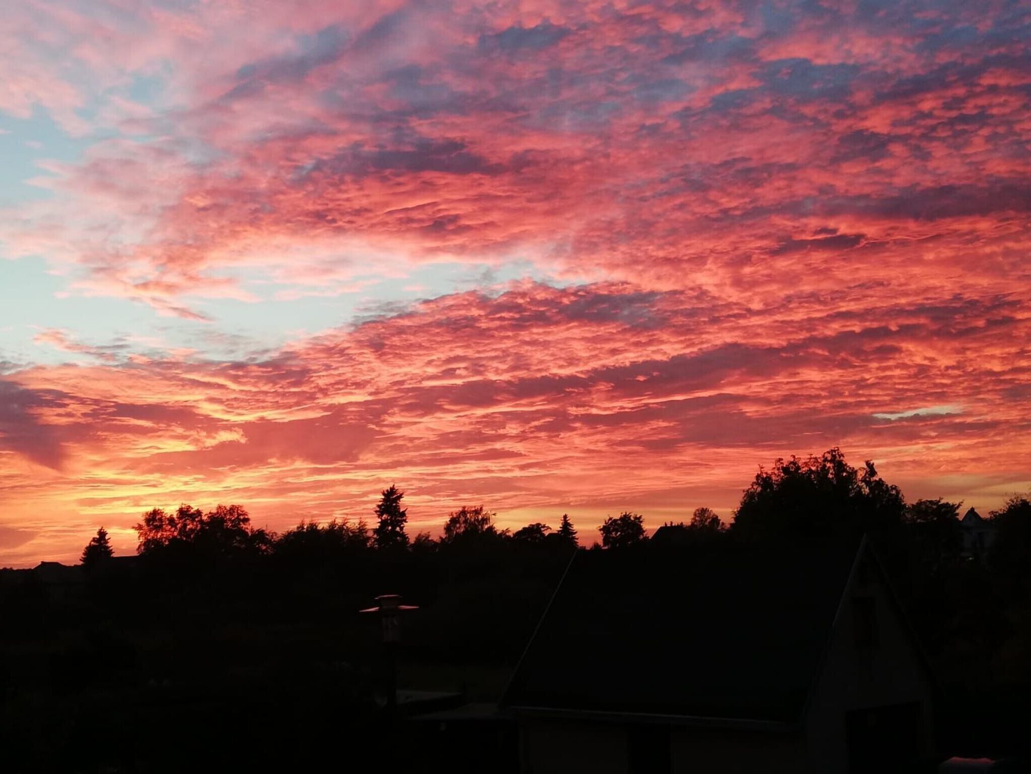 Een zonsondergang met een lucht vol roze en rode wolken.