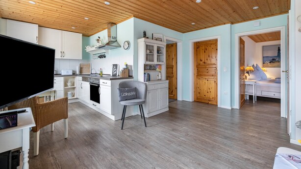 A modern kitchen with wooden cabinets, a built-in oven, and a dining area with a table and chairs. - Apartment 'Doppelhaushälfte Ida' with Private Terrace, Shared Garden and Wi-Fi (Meldorf)