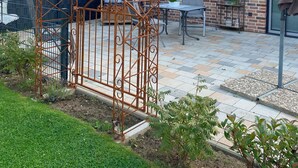 A brick house with a metal gate, outdoor seating, and a garden. - Apartment 'Doppelhaushälfte Ida' with Private Terrace, Shared Garden and Wi-Fi (Meldorf)