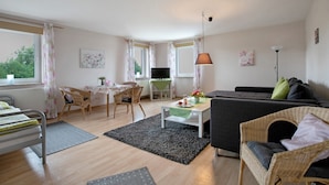 Un salon avec un canapé, une table à manger et des chaises, un téléviseur et une lampe.