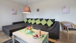 Un salon moderne comprenant un canapé, une table basse, une lampe et deux tableaux accrochés au mur.