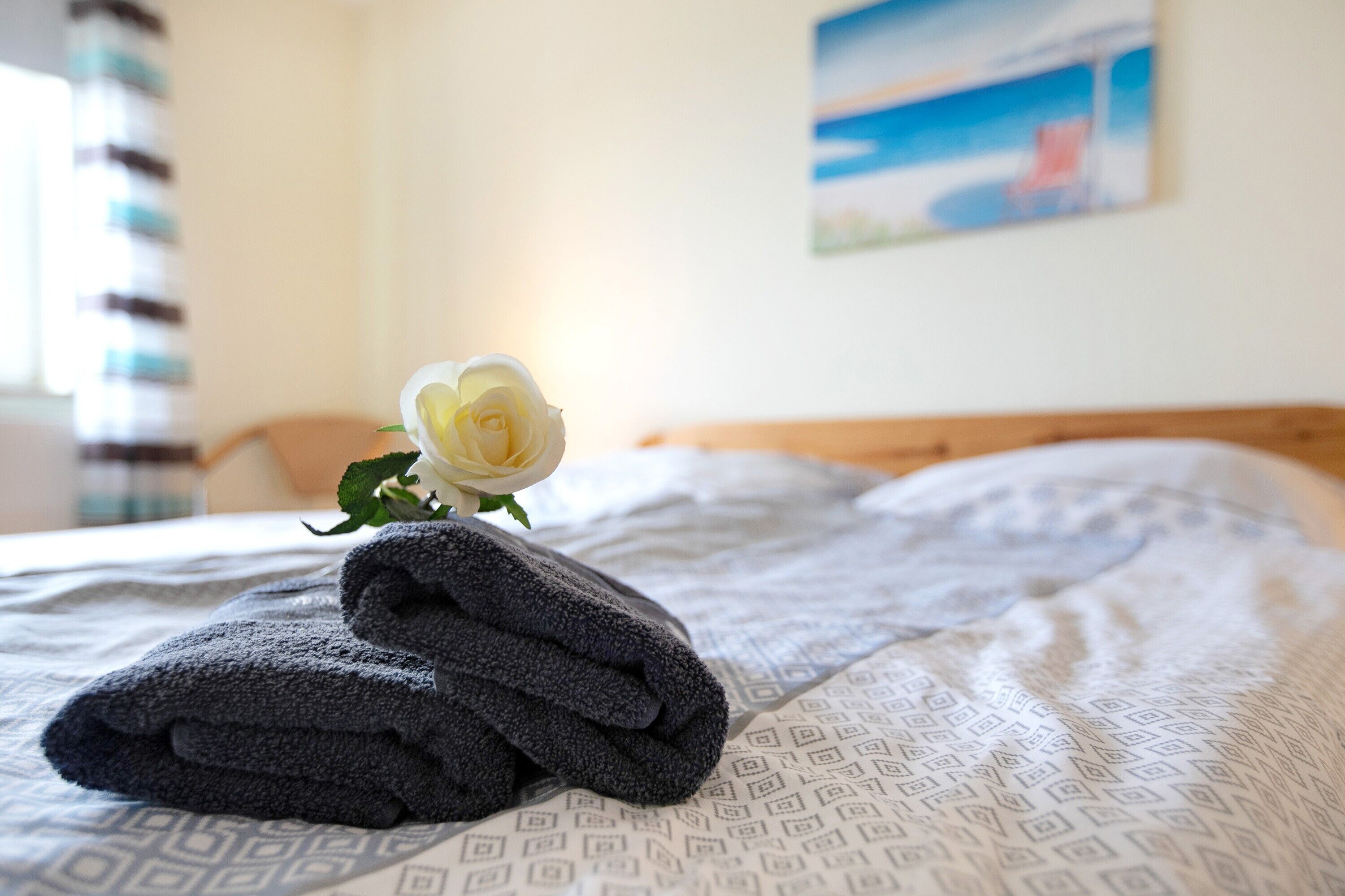 Ein Bett mit gerollten Handtüchern und einer weißen Rose.