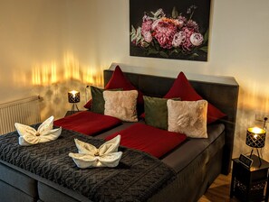 Une chambre à coucher bien rangée, avec un lit, des oreillers, une table de chevet avec une lampe et un tableau accroché au mur.