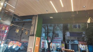 A store with a wooden ceiling and glass walls, displaying various items and advertisements. - Magick Oven (Ujjain)