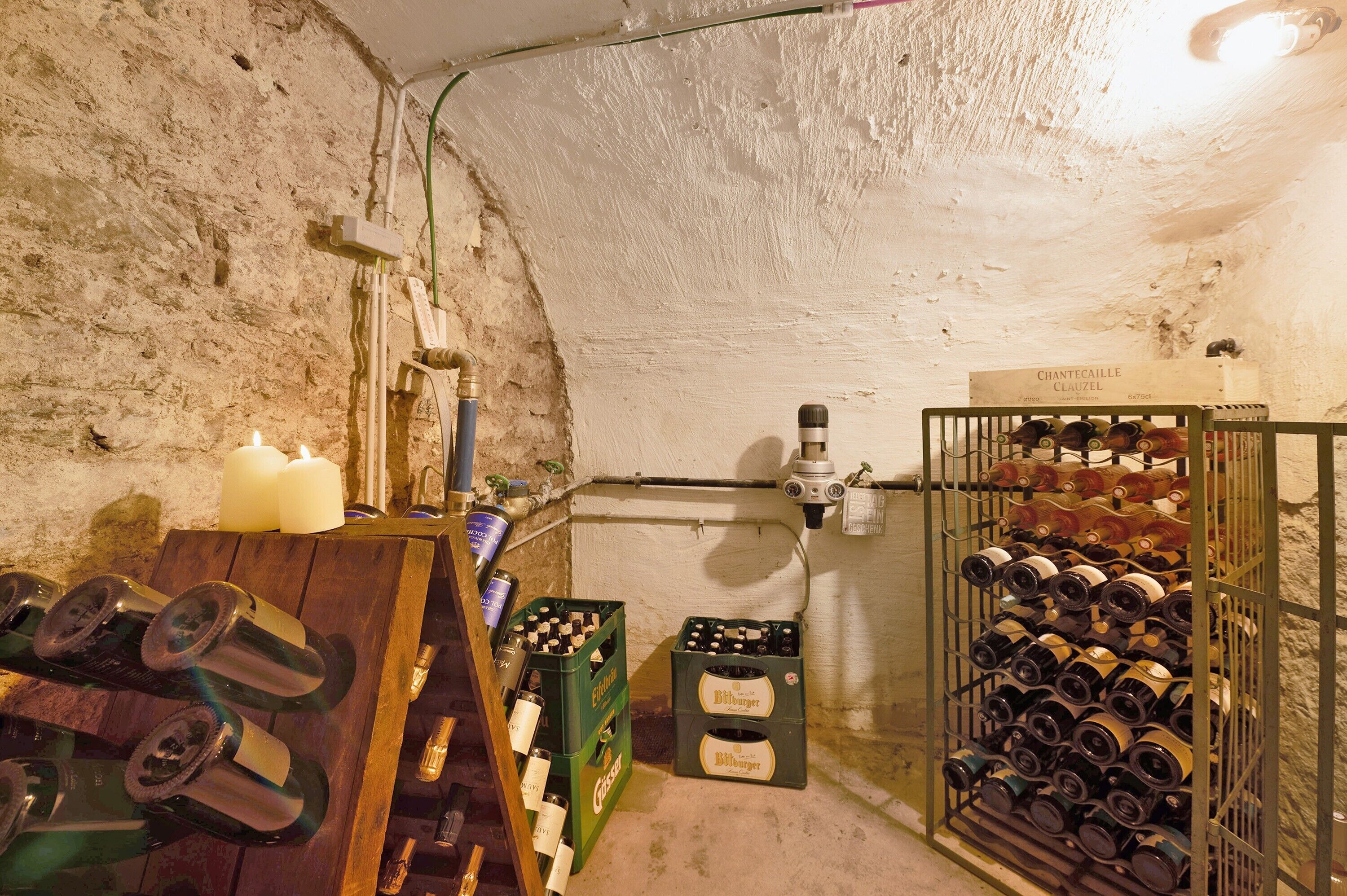 A wine cellar with bottles, crates, and a candle.