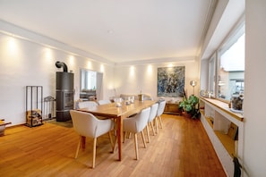 Ein moderner Essbereich mit Holztisch und -stühlen, einem integrierten Herd und einem großen Fenster mit Aussicht.