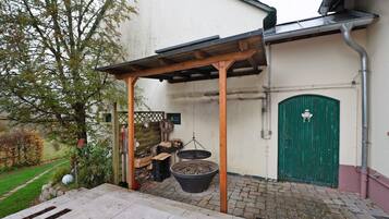 A covered outdoor area with a wooden pergola, a green door, and a large black pot.