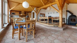 Een ruime keuken met houten balken, een eethoek met een tafel en stoelen, en een stenen openhaard.