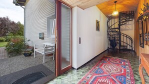 Un interior moderno con una escalera espiral, techo de madera y alfombra estampada.