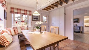Un espace repas avec une table en bois, des bancs et un luminaire suspendu.