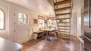 Une cuisine avec un escalier en bois, une table à manger et un banc.