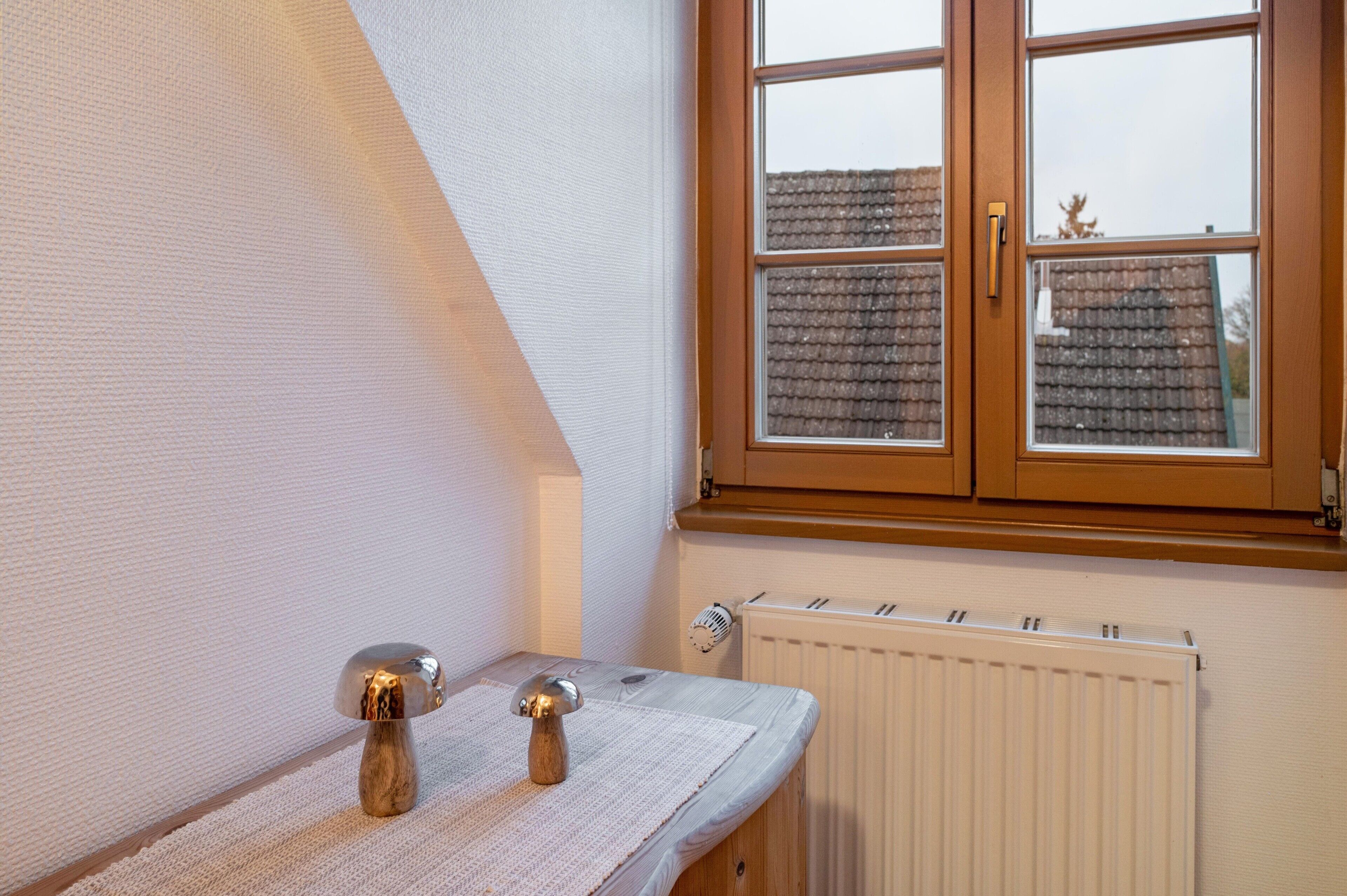A room with a window, radiator, and a small table with a decorative item.