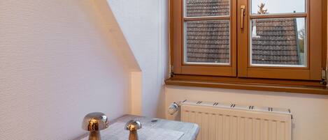 A room with a window, radiator, and a small table with a decorative item.
