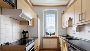 Una cocina compacta con armarios de madera, horno empotrado, lavavajillas y ventana con vistas.