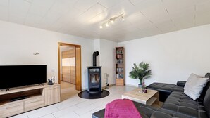 A living room with a flat-screen TV, a sofa, a coffee table, a fireplace, and a bookshelf.