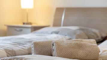 A neatly made bed with a headboard, a bedside lamp, and a nightstand.