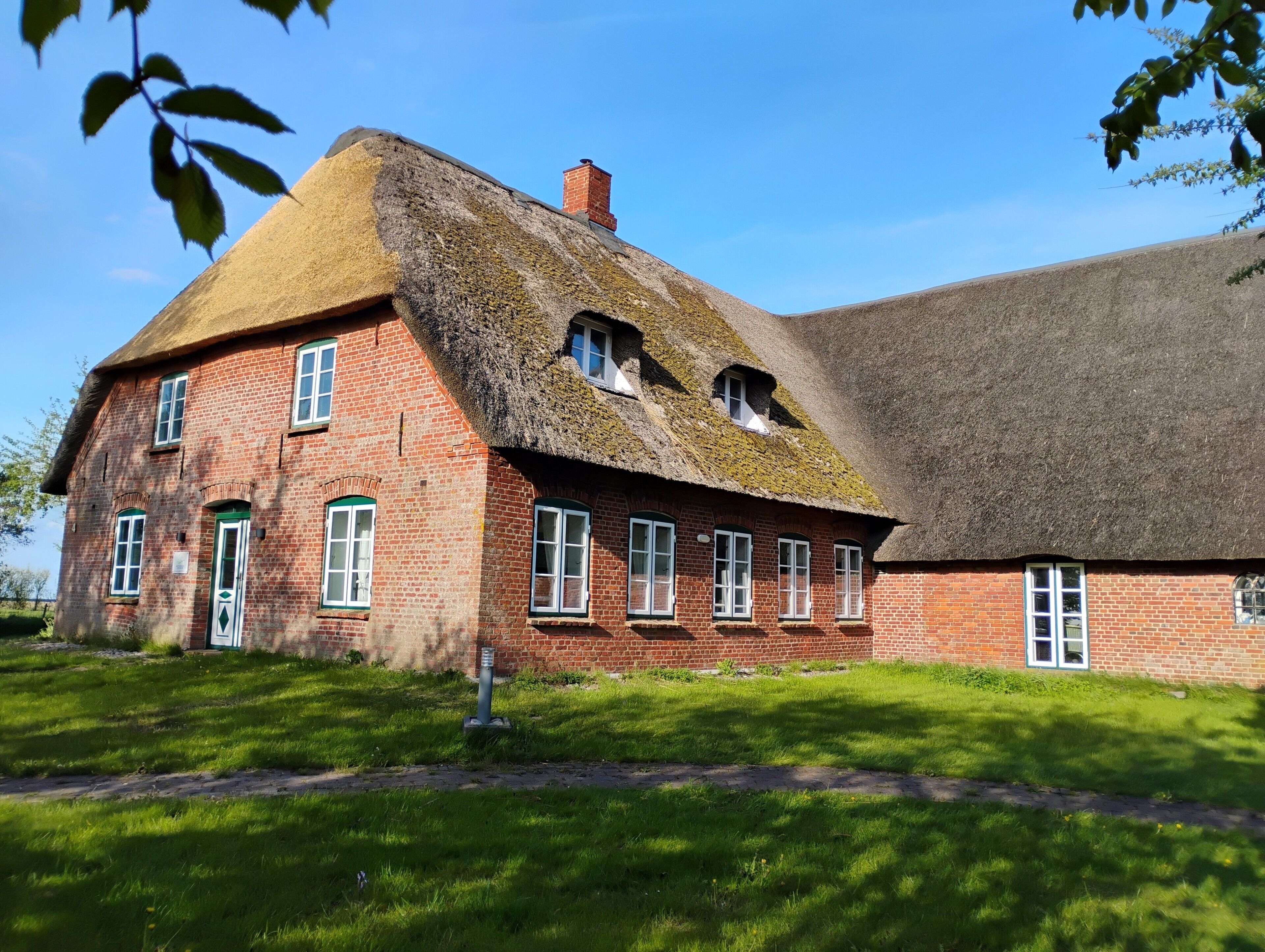 Un bâtiment traditionnel en briques, doté d’un toit de chaume et de nombreuses fenêtres.
