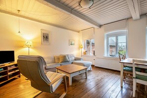 Un salon confortable avec un canapé, une table basse, un téléviseur et une table à manger avec des chaises.