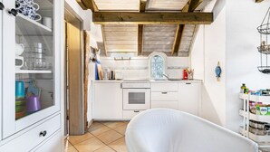 A kitchen with white cabinets, a wooden ceiling, and a window with a view. - Apartment 1 with Shared Garden, Terrace, and Wi-Fi (Rodenäs)
