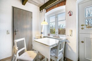 A room with a white desk, chair, and window with curtains.