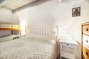 Une chambre avec deux lits, une table de chevet avec une lampe, une commode et un luminaire fixé au mur.