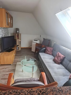 Uma sala de estar estilo loft com televisão, estante e área de estar.