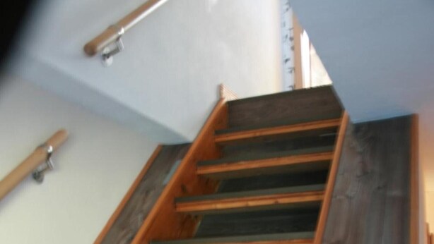 A wooden staircase with a handrail, leading to a landing.