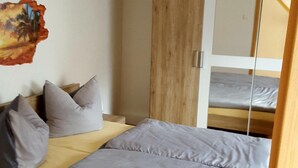 A single bed with a wooden headboard, a mirror, and a painting on the wall.