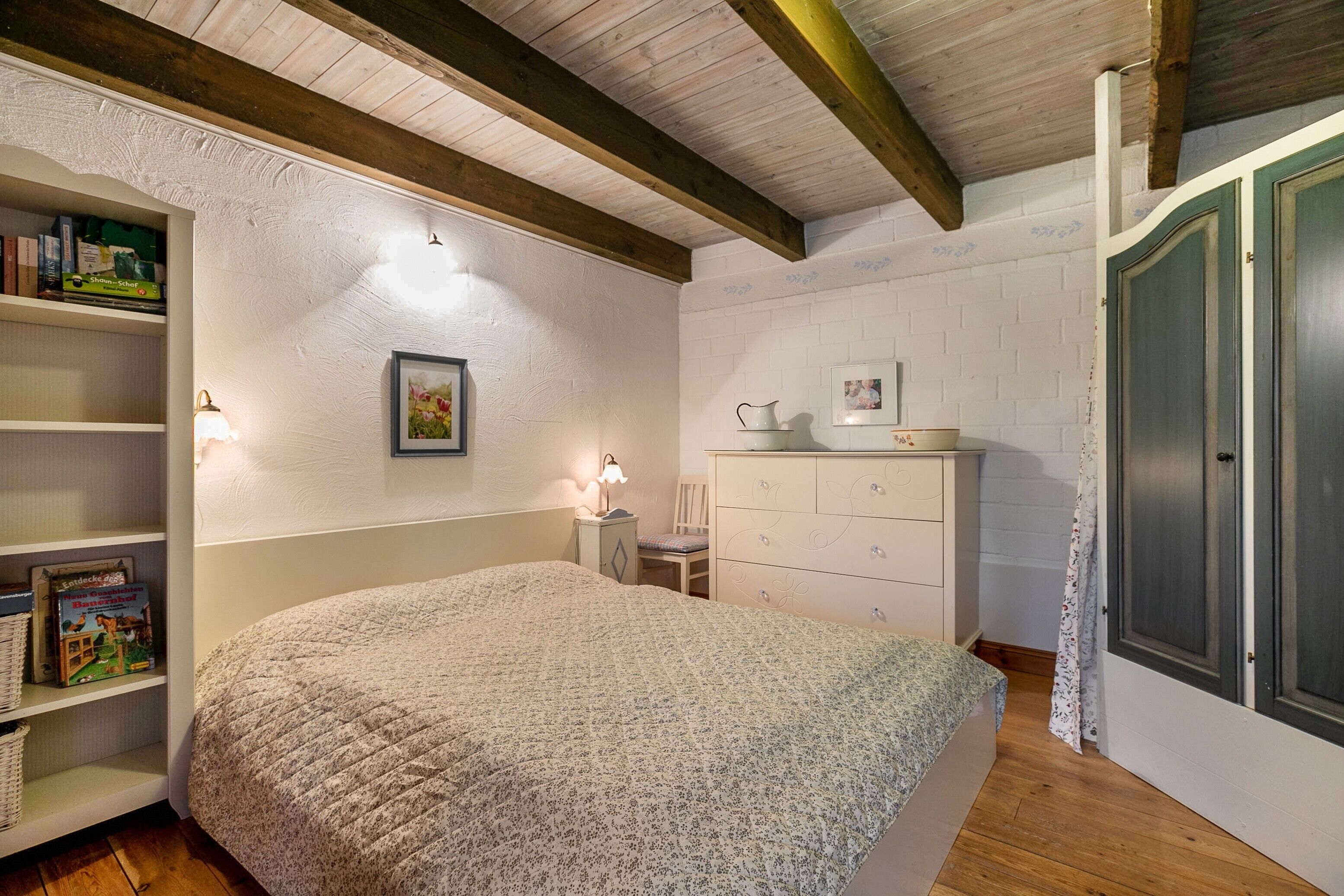 Un dormitorio con cama, mesita de noche, cómoda y estantería.