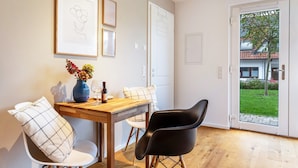 Un comedor con una mesa de madera, dos sillas, un jarrón con flores y obras de arte enmarcadas en la pared.