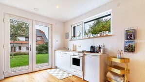 Una cocina moderna con puerta corrediza de vidrio, horno empotrado, refrigerador blanco y carrito dorado.