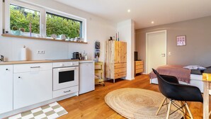 Una cocina moderna con armarios blancos, horno empotrado y ventana con vistas a zonas verdes.