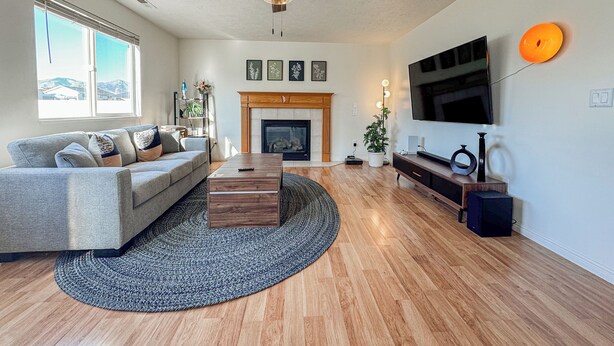 A spacious living room with a large sofa, a coffee table, a fireplace, a television, and a ceiling fan.
