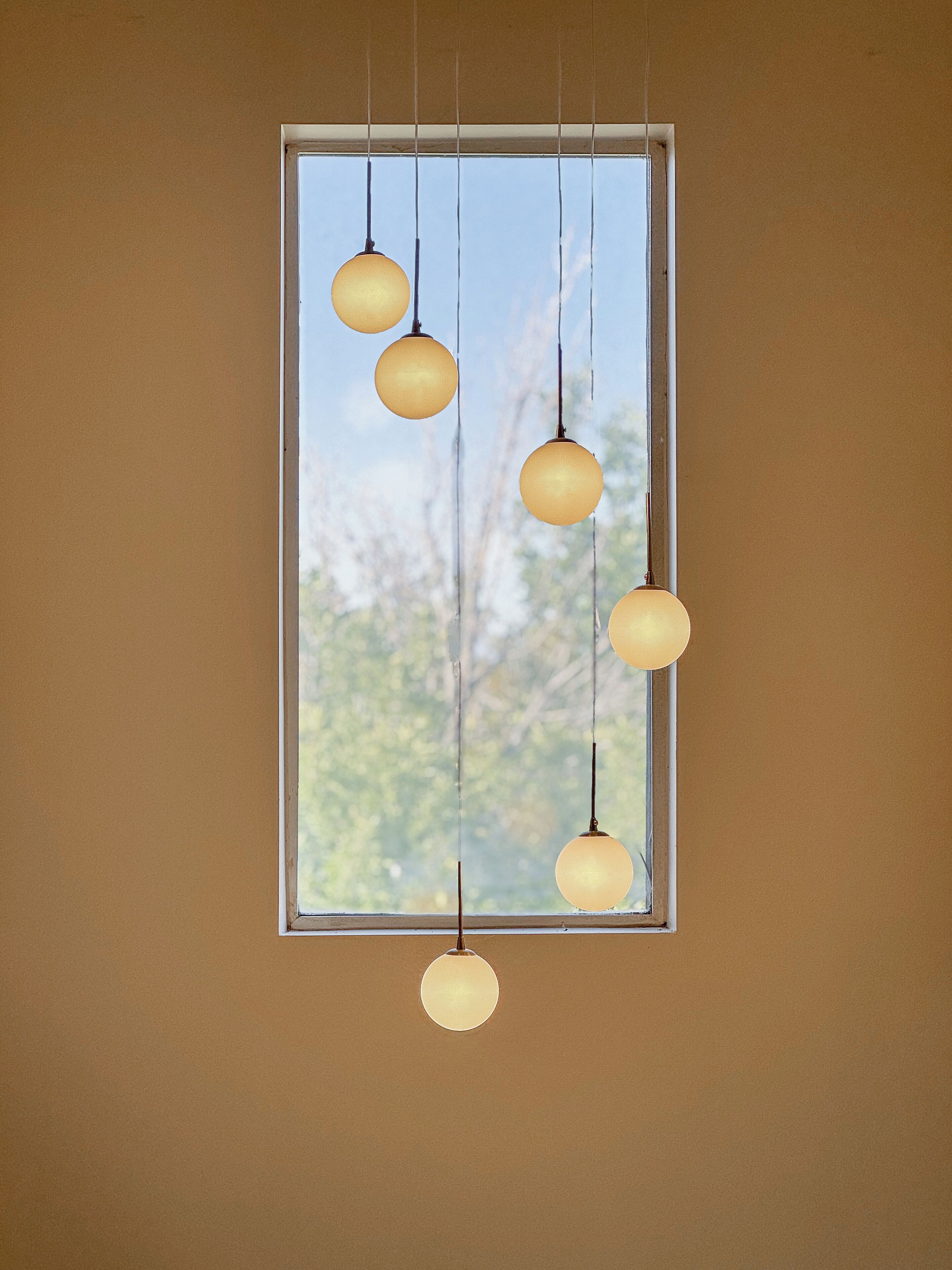 A window with five spherical hanging lights.