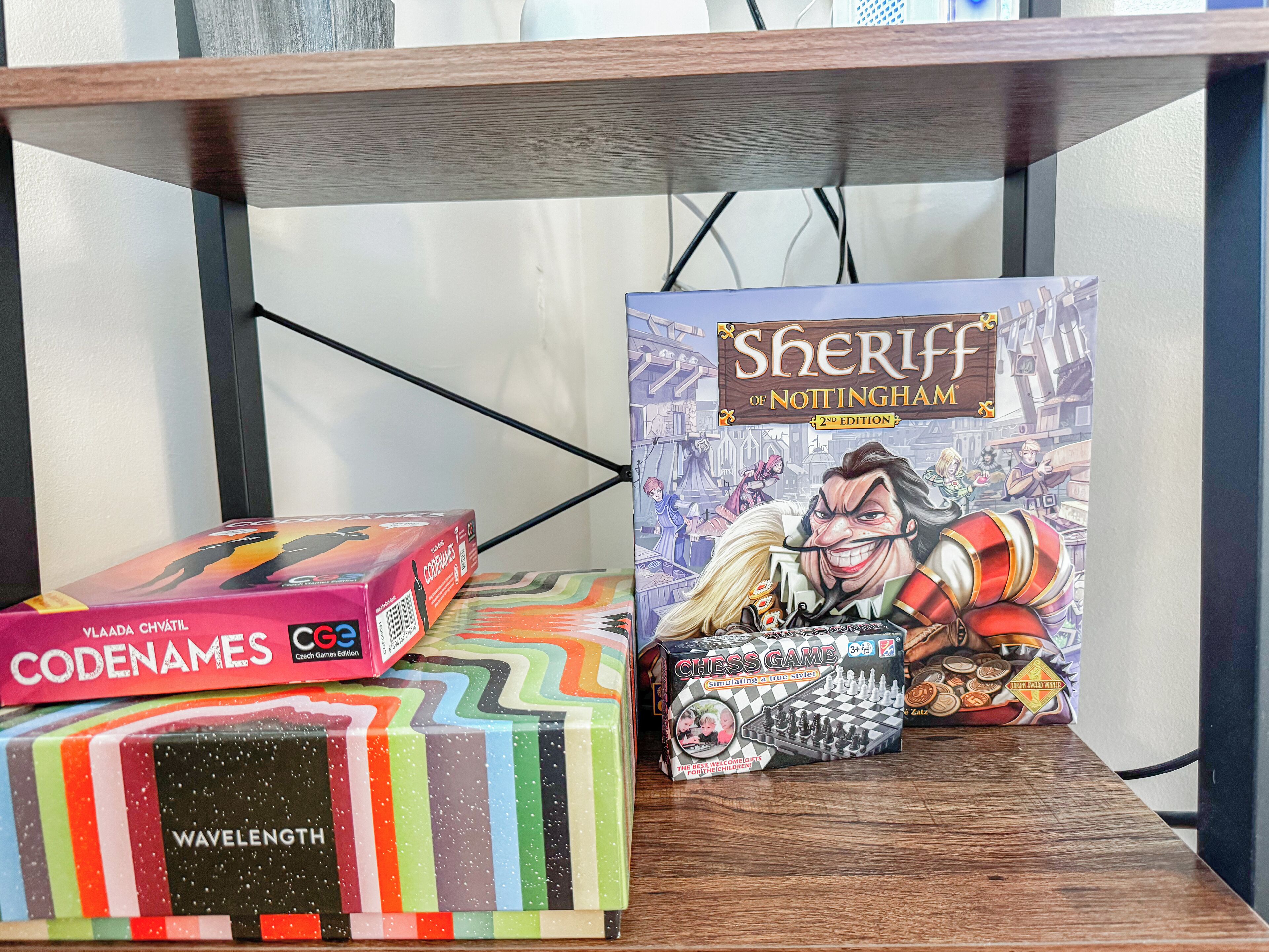 A shelf with various board games, including 'Sheriff of Nottingham' and 'Codenames'.