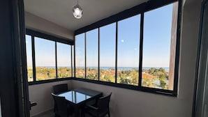 A room with a table and chairs, large windows with a view of a coastal area. - Mersin Panorama Otel (Erdemli)