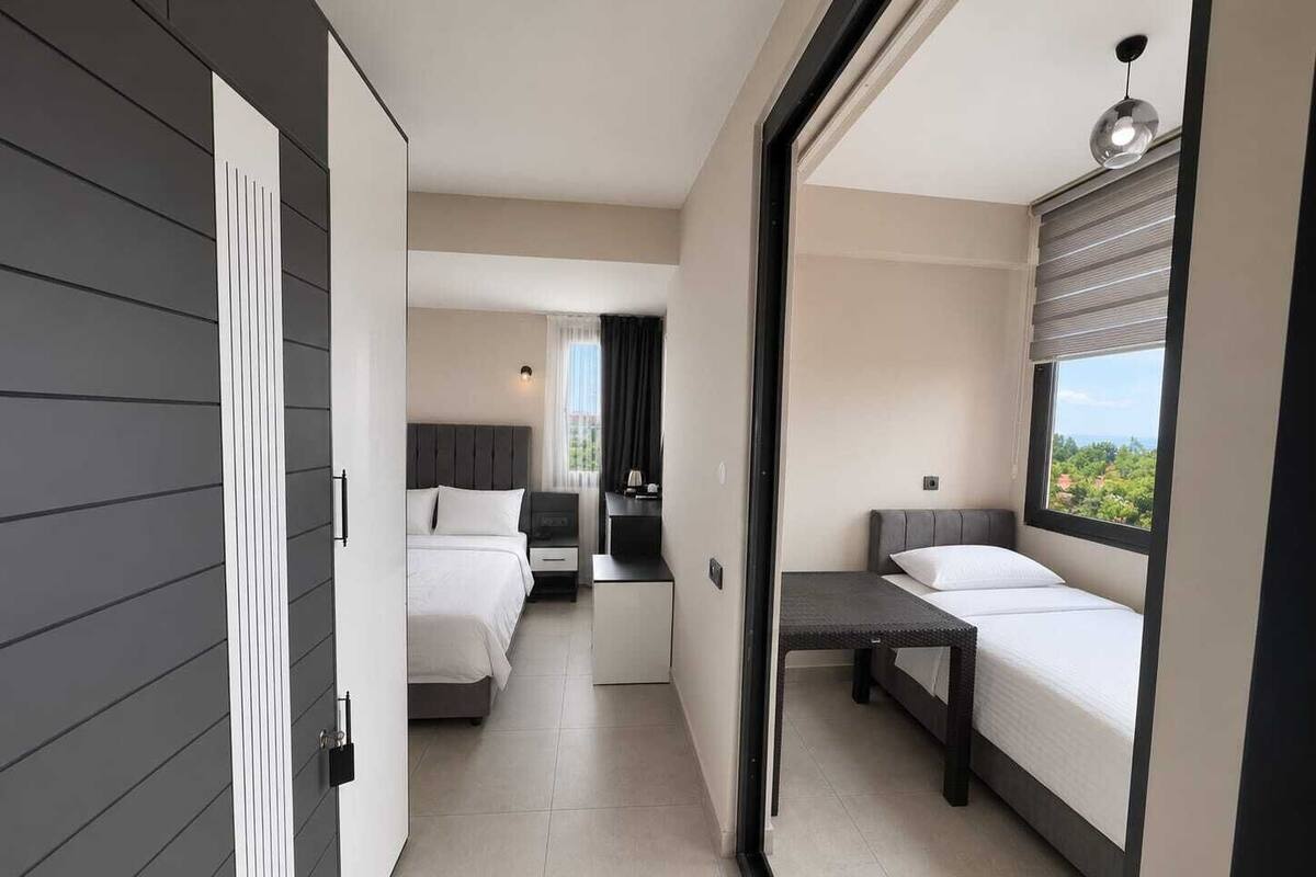 A modern hotel room with a bed, a desk, and a view of the outdoors.