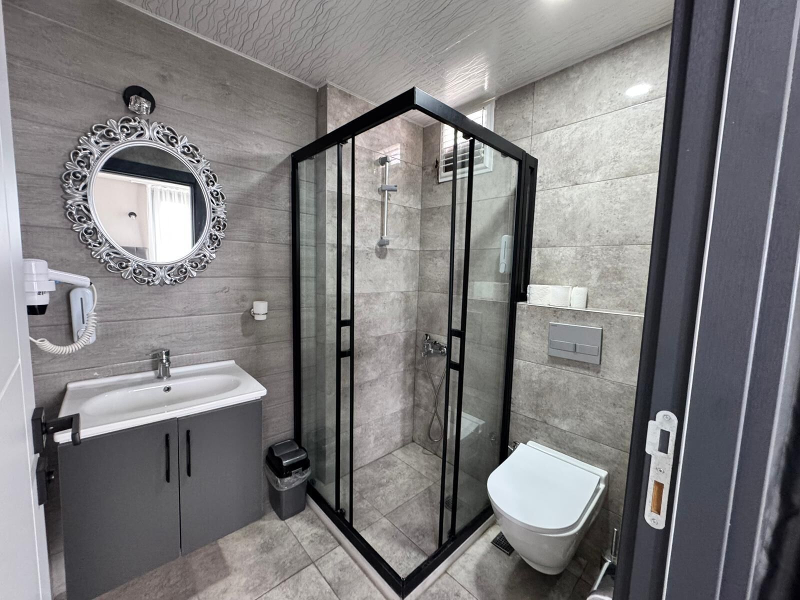 A modern bathroom with a glass-enclosed shower, a white sink, and a toilet.