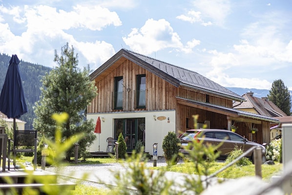 Un bâtiment en bois avec un toit en pente, une entrée bien visible et une voiture garée devant.