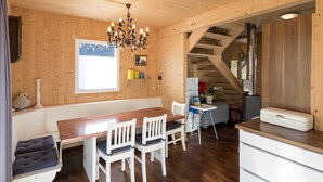 Ein Holzkamin mit einem Esstisch, Stühlen, einer Chandelüster, einer Treppe und einer Küchenzeile.