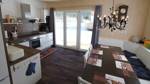 Eine moderne Küche mit Essbereich, Holzböden und Blick auf eine verschneite Landschaft durch Glastüren.