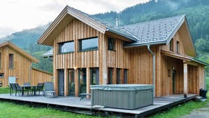 Une cabane en bois dotée d’une terrasse, de grandes fenêtres et d’un bain à remous.