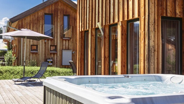 Une cabane en bois avec un jacuzzi et un fauteuil de relaxation.